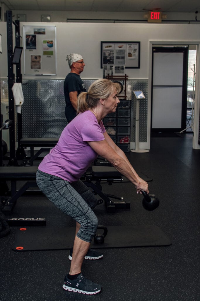 Personal training Naples FL: coach guiding a member through a kettlebell swing